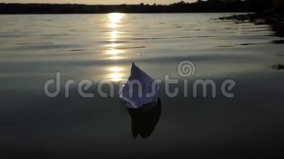 夕阳西下一艘白色的纸船漂浮在湖水中视频的预览图