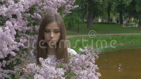 那个年轻的女孩正在享受丁香的香味呼吸着花香视频的预览图