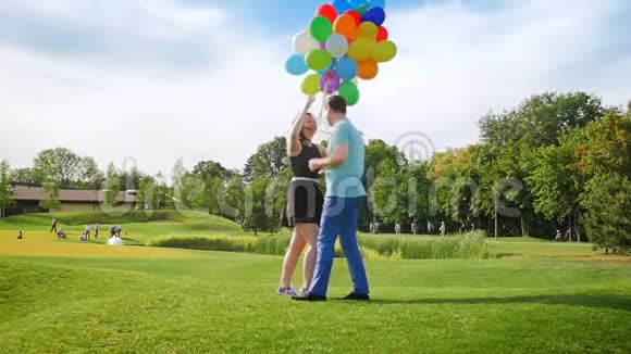 慢动作视频快乐的年轻夫妇拿着气球在公园接吻视频的预览图