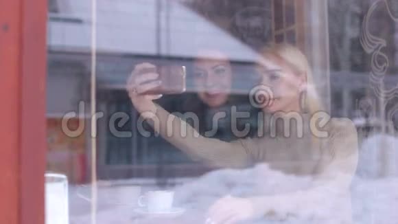 两个女朋友在自拍从窗口从街上看视频的预览图