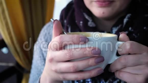 一个年轻女子在咖啡馆里喝着卡布奇诺视频的预览图