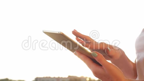 女性手在平板电脑上打字背景是海上日落慢动作视频的预览图