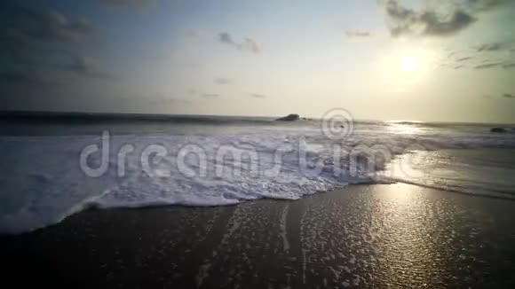 日落时海滩上的风景带着波浪和泡沫视频的预览图