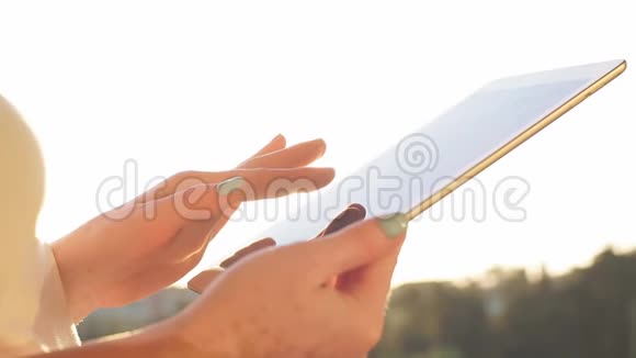 日落时分女性双手在触摸板上的背景下拍摄慢动作视频的预览图