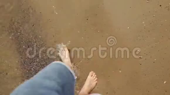 站在沙滩上踏着金沙的年轻人的观点雄腿在海洋附近行走光脚的家伙视频的预览图
