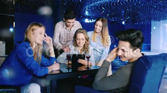 一群年轻人在咖啡馆或餐馆放松使用平板电脑oschayutsya喝葡萄酒或香槟好的视频的预览图