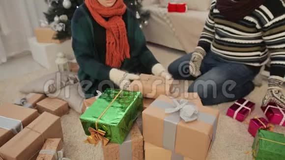 一个年轻的女孩和一个男人正在收集一堆新年礼物圣诞节的主题视频的预览图