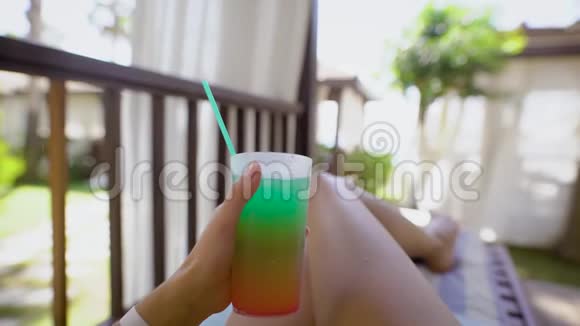 热带女人在酒店露台上展示五颜六色的鸡尾酒和寒冷视频的预览图
