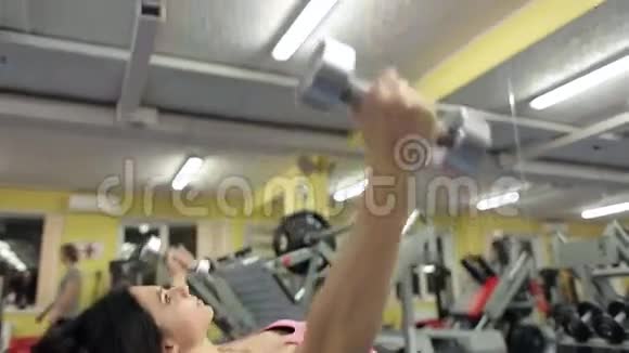 一个年轻健康的女孩在健身房里摇动她的手臂肌肉视频的预览图