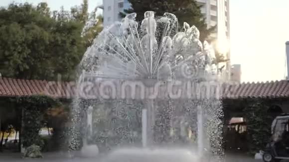 在城市公园的傍晚阳光下闪闪发光的喷泉喷泉溅出慢动作水滴三角形视频的预览图