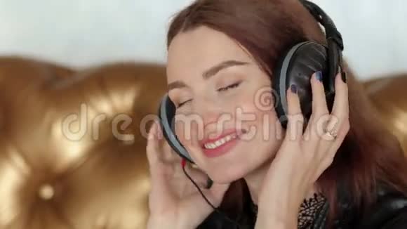 美丽的女孩在耳机上闭着眼睛听音乐视频的预览图