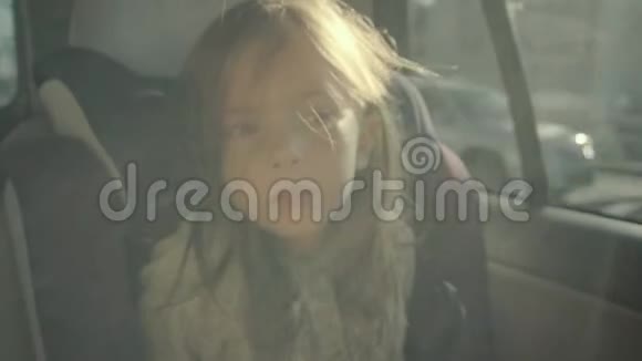 可爱可爱的女孩坐在车里坐在婴儿座椅上看着视频的预览图