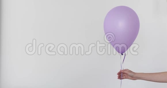 女人手握紫色气球白色背景视频的预览图