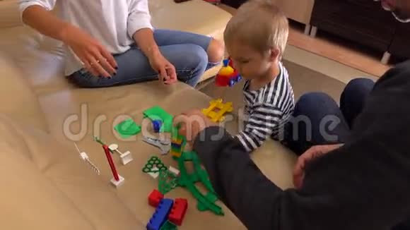 小家庭一起玩塑料玩具建筑父母和他们的孩子有空闲时间在家视频的预览图