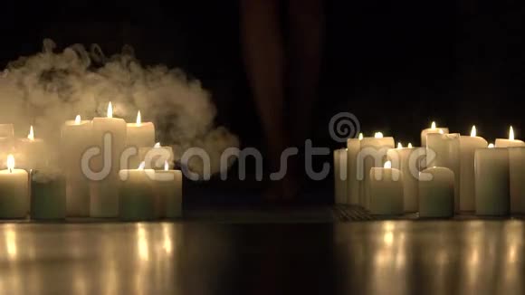 女孩的双腿在黑暗中燃烧蜡烛的烟雾中向前走慢慢地视频的预览图