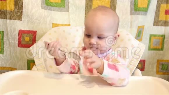 婴儿坐在椅子上吃饭手里拿着勺子视频的预览图