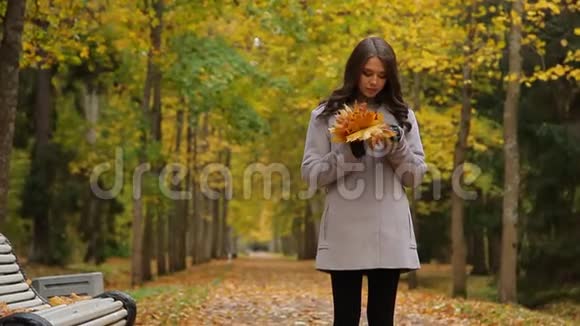 秋天伤心美丽的年轻女子在公园里走来走去坐在长凳上等着别人视频的预览图