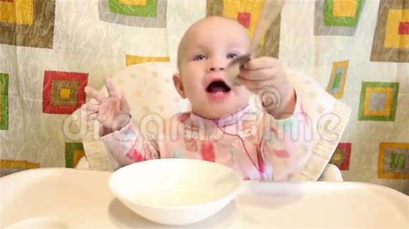 婴儿坐在椅子上吃饭手里拿着勺子视频的预览图