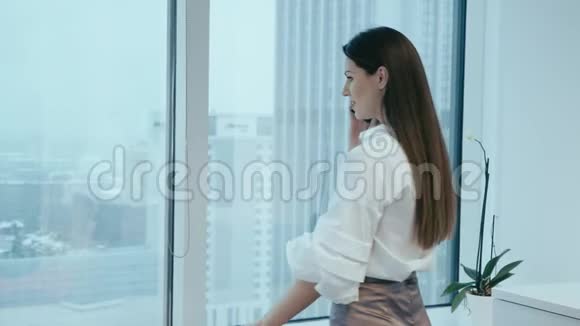 漂亮的女商人在玻璃办公室打电话视频的预览图