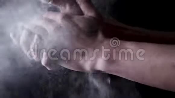黑色背景上有面粉的棉手框架厨师用面粉拍拍手视频的预览图