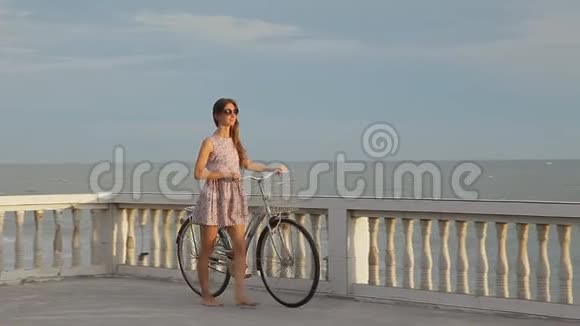 美丽的女孩她的自行车在海滩附近的路堤上视频的预览图