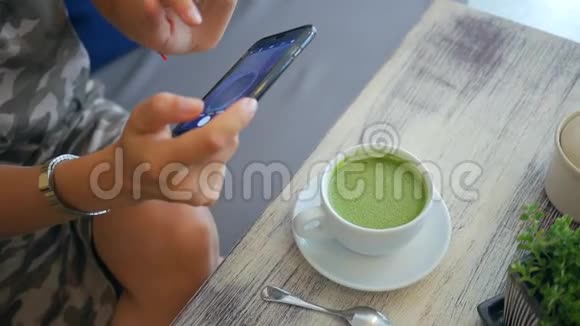 女孩在餐厅或咖啡厅的杯中拍摄抹茶绿茶车床纯素健康饮品HD慢速运动泰国视频的预览图