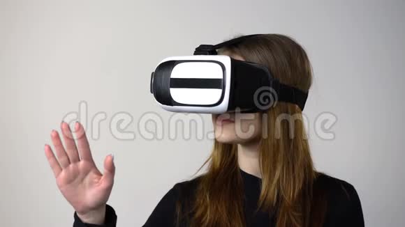 穿着虚拟现实护目镜的休闲年轻女子移动手视频的预览图