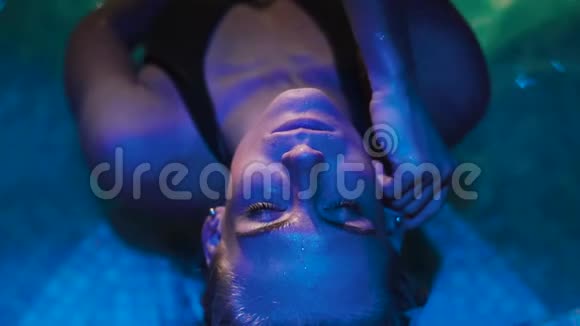 躺在按摩浴缸边缘的女人的特写蓝色的灯光视频的预览图