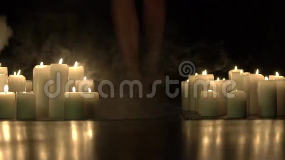 女孩的双腿在黑暗中燃烧的蜡烛之间向前走慢慢地视频的预览图