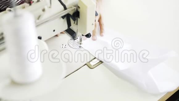 一位女士在工厂缝制一件蓝白衬衫的俯视图视频的预览图
