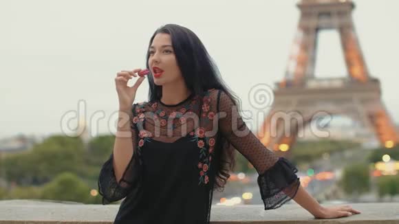 巴黎女人微笑着吃着巴黎艾菲尔铁塔上的法国糕点通心粉视频的预览图