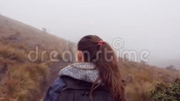 在潮湿多雾的天气里穿着雨衣和背包在山上行走的徒步旅行妇女小女孩在山径上视频的预览图