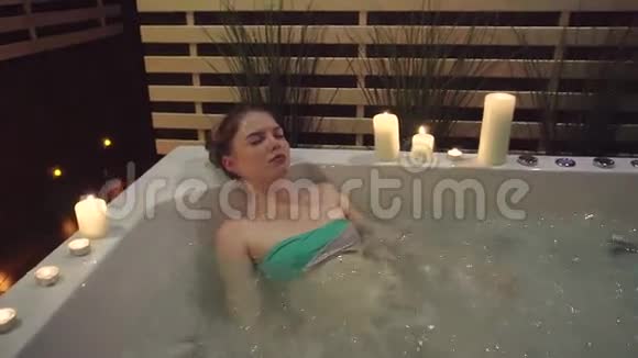 一个年轻的女孩躺在一个带海盐的按摩浴缸里在艰难的一天之后休息视频的预览图