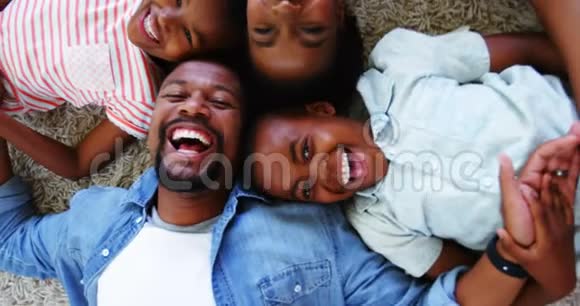 幸福的父母和孩子躺在地毯上的画像视频的预览图