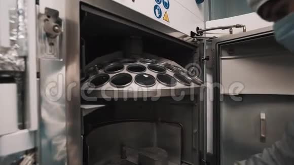 穿长袍和橡胶手套的工程师在实验室的烤箱内操作零件视频的预览图