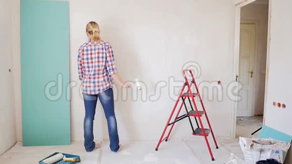 年轻女子在新公寓画墙时跳舞的慢镜头视频的预览图