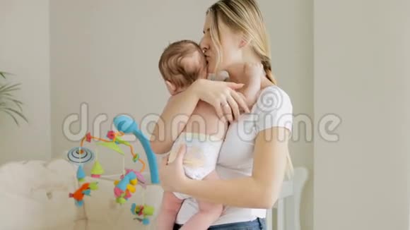 美丽的微笑的女人抱着她3个月大的男孩手牵着孩子卧室视频的预览图