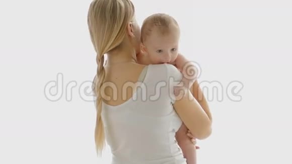 漂亮的年轻女人在大窗户前拥抱她3岁的小男孩白人背景的人视频的预览图