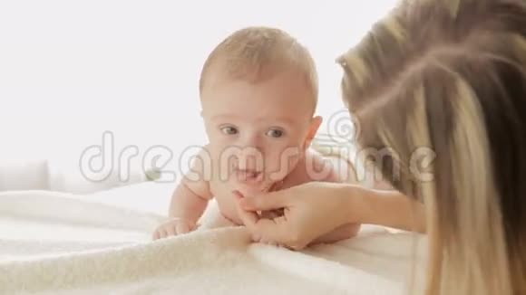 年轻母亲的特写镜头3个月大的小男孩在床上爬行视频的预览图