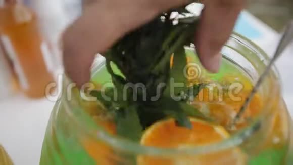 双手合拢将一小撮薄荷放入一碗天然柠檬水中视频的预览图