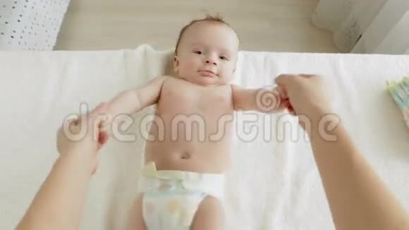在卧室里躺在换洗的桌子上按摩3个月大的婴儿的年轻母亲的POV照片婴儿健康成长的概念视频的预览图
