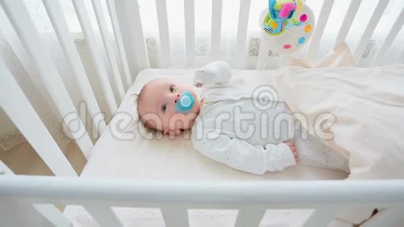 可爱的3个月大的婴儿躺在婴儿床上爱抚的父母视频的预览图
