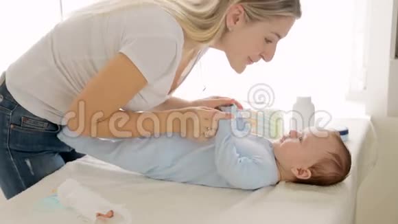可爱的3个月大的男孩躺在变化和笑而母亲亲吻和玩他视频的预览图