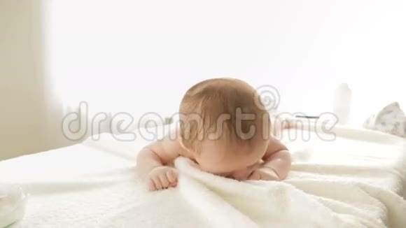 可爱的3个月大的男孩躺在床上试图爬行视频的预览图