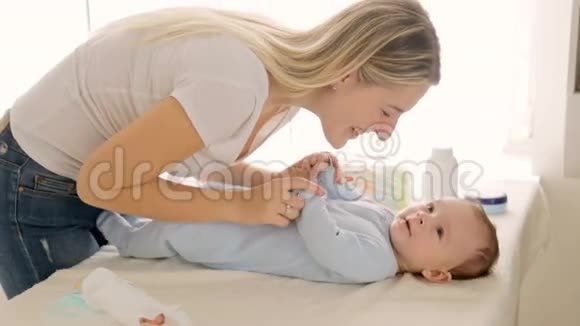 年轻漂亮的妈妈吻着她3个月大的男孩躺在更衣室里视频的预览图