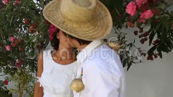 新娘和新郎在开花树的背景下接吻波霍风格希腊视频的预览图