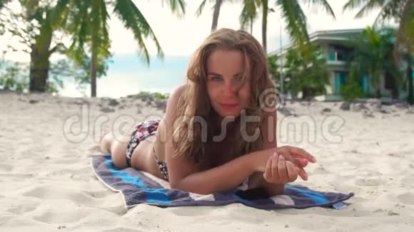 描绘年轻女子暑假在沙滩上晒太阳美丽的女人在海边晒黑视频的预览图