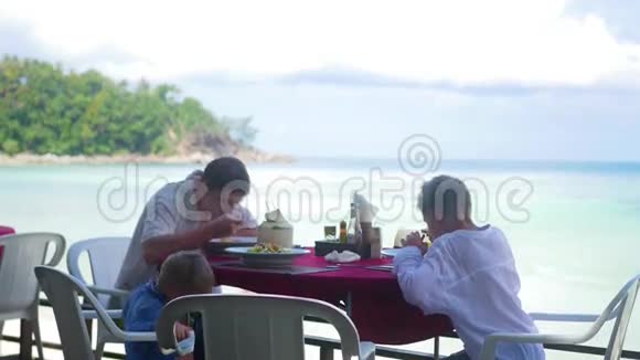 一家有孩子的家庭在海滩上的一家餐馆吃饭户外食品视频的预览图