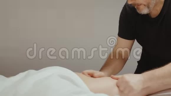 男性按摩师做腿部髋部按摩接受复健程序的妇女视频的预览图