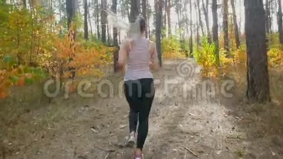 早晨年轻女子在松林中缓慢地奔跑视频的预览图